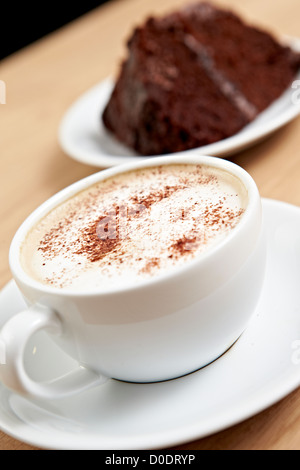Caffè caldo latte o cappuccino e torta al cioccolato servito con un pizzico in una caffetteria. Foto Stock