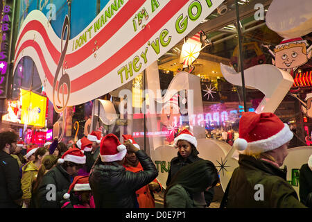 Novembre 22, 2012, New York, NY. Persone che indossano Santa Claus cappelli supporto in linea per prendere vantaggio di vendita vacanza al Times Square Toys R Us store, che apre alle 8 del pomeriggio del Giorno del Ringraziamento vacanza Foto Stock