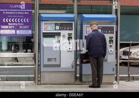 Uomo di comprare un biglietto dalla macchina su piattaforma in Luas sistema di Ferrovia Leggera di stazione del tram nella città di Dublino Sud Irlanda Eire Foto Stock