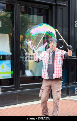 Irlandese intrattenitore di strada facendo una grande bolla con due bastoni nel centro città di Grafton Street, Dublin, Irlanda meridionale, Eire Foto Stock