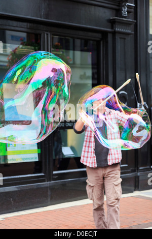 Irlandese intrattenitore di strada facendo 2 bolle di grandi dimensioni con due bastoni nel centro città di Grafton Street, Dublin, Irlanda meridionale, Eire Foto Stock