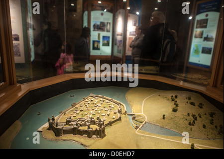 CAERNARFON, Galles: Un dettagliato modello architettonico mostra come il castello di Caernarfon sarebbe apparso durante il suo periodo medievale, esposto come parte di una mostra museale sulla fortezza. Il modello in scala offre ai visitatori una vista completa della struttura e del design originali del castello. Il castello di Caernarfon, costruito da Edoardo i durante la sua conquista del Galles alla fine del XIII secolo, servì come residenza reale e roccaforte militare. Il castello è rinomato per le sue caratteristiche torri poligonali e la muratura a fasce, ispirate alle mura di Costantinopoli. Oggi, il sito patrimonio dell'umanità dell'UNESCO attrae Foto Stock