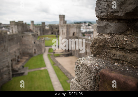 CAERNARFON, Galles, il cortile interno del castello di Caernarfon visto dalle merlature della fortezza medievale. Costruito tra il 1283 e il 1287 da Edoardo i durante la sua conquista del Galles, il castello è rinomato per le sue caratteristiche torri poligonali e la muratura a fasce. La fortezza servì come centro amministrativo del Galles settentrionale e fu il luogo di nascita del primo principe inglese di Galles nel 1284. Il castello di Caernarfon fa parte dell'anello di ferro di Edoardo i nel Galles settentrionale ed è stato dichiarato patrimonio dell'umanità dell'UNESCO nel 1986. Il castello rimane uno dei più bei esempi di fine XIII e EAR Foto Stock