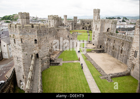 CAERNARFON, Galles, il cortile interno del castello di Caernarfon visto dalle merlature della fortezza medievale. Costruito tra il 1283 e il 1287 da Edoardo i durante la sua conquista del Galles, il castello è rinomato per le sue caratteristiche torri poligonali e la muratura a fasce. La fortezza servì come centro amministrativo del Galles settentrionale e fu il luogo di nascita del primo principe inglese di Galles nel 1284. Il castello di Caernarfon fa parte dell'anello di ferro di Edoardo i nel Galles settentrionale ed è stato dichiarato patrimonio dell'umanità dell'UNESCO nel 1986. Il castello rimane uno dei più bei esempi di fine XIII e EAR Foto Stock