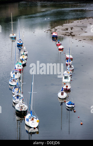 Barche sul fiume Seiont | CAERNARFON, Galles — Barche a vela sono ancorate sul fiume Seiont, viste dalle torri del castello di Caernarfon all'attracco di marea dove il fiume incontra lo Stretto di Menai. Edoardo I iniziò a costruire la fortezza qui nel 1283 sotto la guida del mastro muratore Giacomo di San Giorgio, posizionandola per controllare questa via navigabile e il commercio marittimo che ha a lungo sostenuto. Le torri elevate del castello, parte del suo disegno difensivo originale, offrono ancora viste panoramiche sull'acqua sottostante. Foto Stock