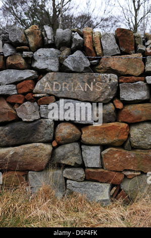 Muro di pietra costruire nel North York Moors con la pietra nome wallers Adrian scavata nella parete. Foto Stock