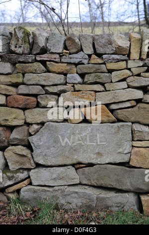 Muro di pietra costruire nel North York Moors con la pietra nome wallers Adrian scavata nella parete. Foto Stock