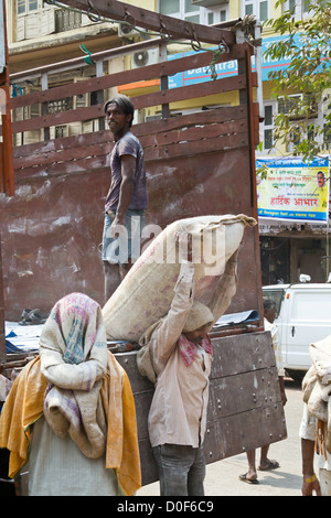 I lavoratori lo scarico di un carrello con sacchi di cemento in Mumbai, India Foto Stock