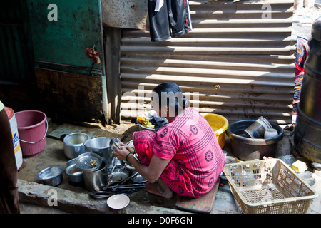 Donna lavando i piatti su strada nella baraccopoli di Dharavi in Mumbai, India Foto Stock