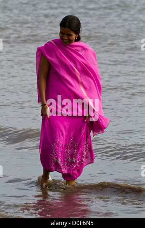 Donna con tradizionale sari nell'oceano sulla Chowpatty Beach in Mumbai, India Foto Stock