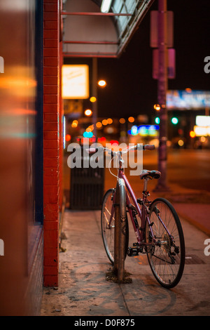 Bicicletta Rosa si è bloccato su un marciapiede illuminato da memorizzare segni Foto Stock