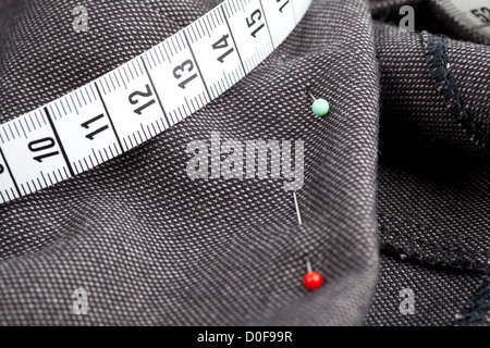 Perni e nastro di misurazione sul tessuto, pronti per la cucitura. Foto Stock
