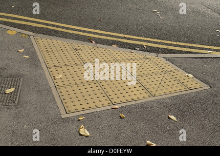 Pavimentazioni tattili in corrispondenza del punto di attraversamento di una strada per aiutare i non vedenti di evitare situazioni di pericolo. Foto Stock