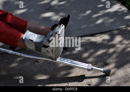 Una donna si appoggia la sua ferita al piede su una stampella Foto Stock