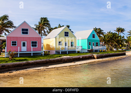 Color pastello cottage lungo l'acqua con palme da cocco sulla Green Turtle Cay, Bahamas. Foto Stock