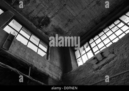 Finestre rotte muro di cemento e soffitto in fabbrica abbandonati. In bianco e nero. Foto Stock