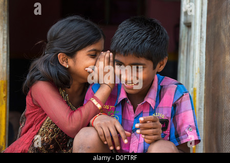 Giovane ragazza indiana whispering ad un ragazzo al di fuori delle loro zone rurali viilage indiano home. Andhra Pradesh, India Foto Stock