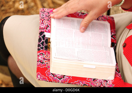 Donna che legge la Bibbia mentre siede su Un Park Bench a Central Park New York City Foto Stock