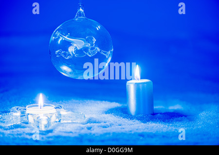 Le decorazioni di Natale con un angelo trasparente ninnolo e candele sulla neve. Foto Stock