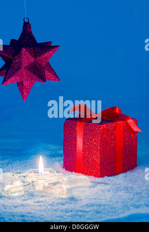 Red regalo di Natale e a forma di stella ninnolo a lume di candela sulla neve. Copia dello spazio. Foto Stock