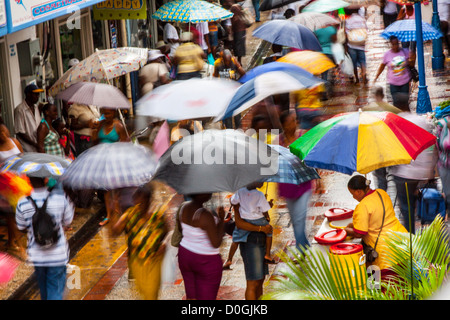 Affollata strada commerciale area in Bridgetown in un giorno di pioggia con persone ombrelli azienda, Barbados, West Indies Foto Stock