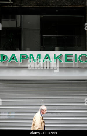 Salonicco, Grecia. Novembre 26, 2012. Un uomo anziano passa davanti ad una farmacia chiusa. 48 ore di sciopero da farmacie in tutto il paese e si fermano contemporaneamente somministrare farmaci sul credito ai membri dei servizi sanitari nazionali (EOPYY) chi dovrà pagare di tasca propria e la rivendicazione l'importo del fondo. Foto Stock