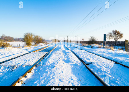 In inverno la neve su binari ferroviari in esecuzione in una linea retta attraverso il Nottinghamshire campagna, England, Regno Unito Foto Stock