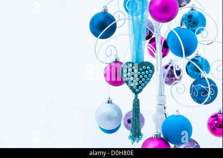 Colorati cuore di Natale e baubles pende da una bianca decorativa di un supporto in metallo Foto Stock