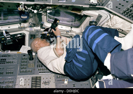 STS-95 Payload Specialist John Glenn si posiziona a prendere le foto dalla scoperta a poppa del ponte di volo windows sul giorno del volo Foto Stock