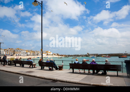 La Gente seduta sul lungomare a St Ives in una giornata di sole. Foto Stock