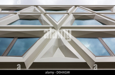 Moderna facciata di un edificio costituito da triangoli e windows in cui riflette il cielo Foto Stock