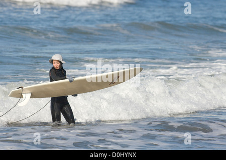 Surfer il prelievo di bordo con onde che si infrangono a. Foto Stock