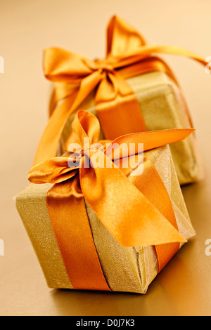 Due confezioni regalo in oro carta di avvolgimento con nastro e prua Foto Stock