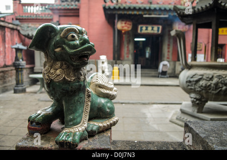 La città di HO CHI MINH, Vietnam - Un piccolo cane verde sta di guardia al di fuori dell'entrata alla Pagoda dell'Imperatore di Giada nella Da Kao distretto della città di Ho Chi Minh, Vietnam. Il tempio Cinese è stato costruito nel 1909 e contiene gli elementi di entrambi i buddisti e taoisti religioni. Foto Stock