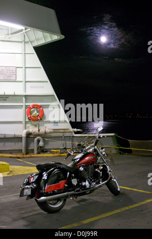 Un motociclo è parcheggiato sul Mulkiteo, nello Stato di Washington, USA deck traghetto mentre viene trasportato attraverso Puget Sound di notte. Foto Stock