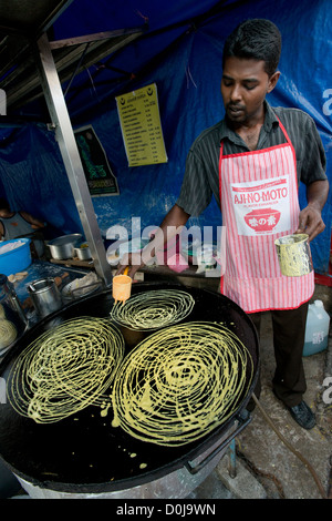 Un uomo indiano prepara spuntini saporiti in Georgetown's Little India, Penang, Malaysia Foto Stock