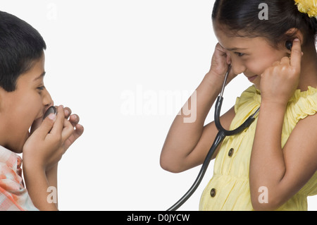 Ragazzo parlando in uno stetoscopio e una ragazza di ascolto Foto Stock