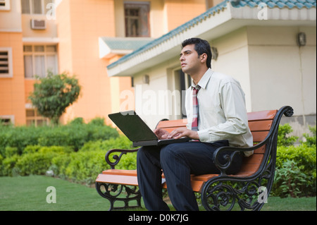 Imprenditore seduta sul banco di lavoro e utilizzando un computer portatile Foto Stock