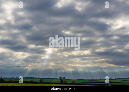 Cielo di sera su terreni agricoli con raggi di sole rompere attraverso le nuvole Foto Stock