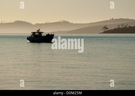 Barca da pesca ormeggiate di di Gordon Tasmania Australia. Early Morning mist si insinua tra le colline di massa posteriore Foto Stock