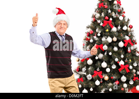 Una felice coppia gentleman dando Thumbs up con albero di natale in background Foto Stock