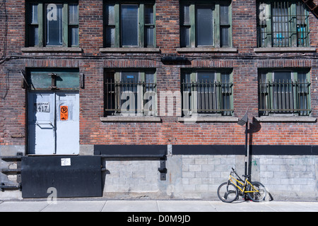 Il vecchio edificio di mattoni e di biciclette appoggiata contro il muro nel centro cittadino di Montreal, provincia del Québec in Canada. Foto Stock