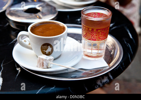Il caffè turco è servita in un tradizionale bagno turco tazza di caffè in un  vassoio di rame Un bicchiere di acqua con un petalo di rosa e le delizie  turche sul