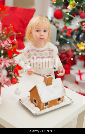 Ritratto di bambino mangiare i cookie nei pressi di Natale Gingerbread house Foto Stock