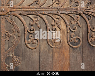 Medievale decorativo di elementi in ferro battuto montato su una vecchia porta di legno Foto Stock