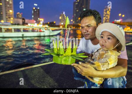 Nov. 28, 2012 - Bangkok, Tailandia - un uomo aiuta a suo figlio lanciare loro krathong durante il Loy Krathong al Wat Yannawa in Bangkok. Loy Krathong ha luogo la sera della luna piena del dodicesimo mese in tailandese tradizionale calendario lunare. Nel calendario occidentale questo di solito cade nel mese di novembre. Loy significa 'flottante', mentre krathong si riferisce al solito lotus-contenitore sagomato che galleggia sull'acqua. Krathongs tradizionali sono fatti di strati del tronco di un albero di banana o uno spider lily impianto. Credito: ZUMA Press, Inc. / Alamy Live News Foto Stock