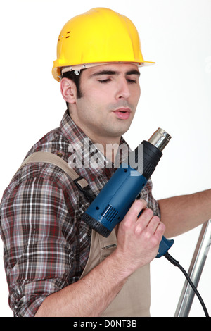 Tradesman soffia sulla sua pistola a vite Foto Stock