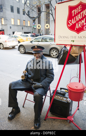 Afro-americano di campana di volontariato-suoneria raccoglie donazioni per l'Esercito della salvezza di fronte Saks Fifth Avenue a Manhattan. Foto Stock