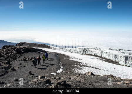 MT KILIMANJARO, Tanzania - un gruppo di alpinisti iniziano la discesa dalla cima del Monte Kilimanjaro, con ghiacciai permanenti al loro diritto. Foto Stock