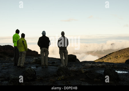 MONTE KILIMANJARO, Tanzania: Un gruppo di quattro escursionisti guarda le nuvole sottostanti dal Moir Hut Camp (13.660 metri) prima di salire sulla Lemosho Route del monte Kilimanjaro. Foto Stock